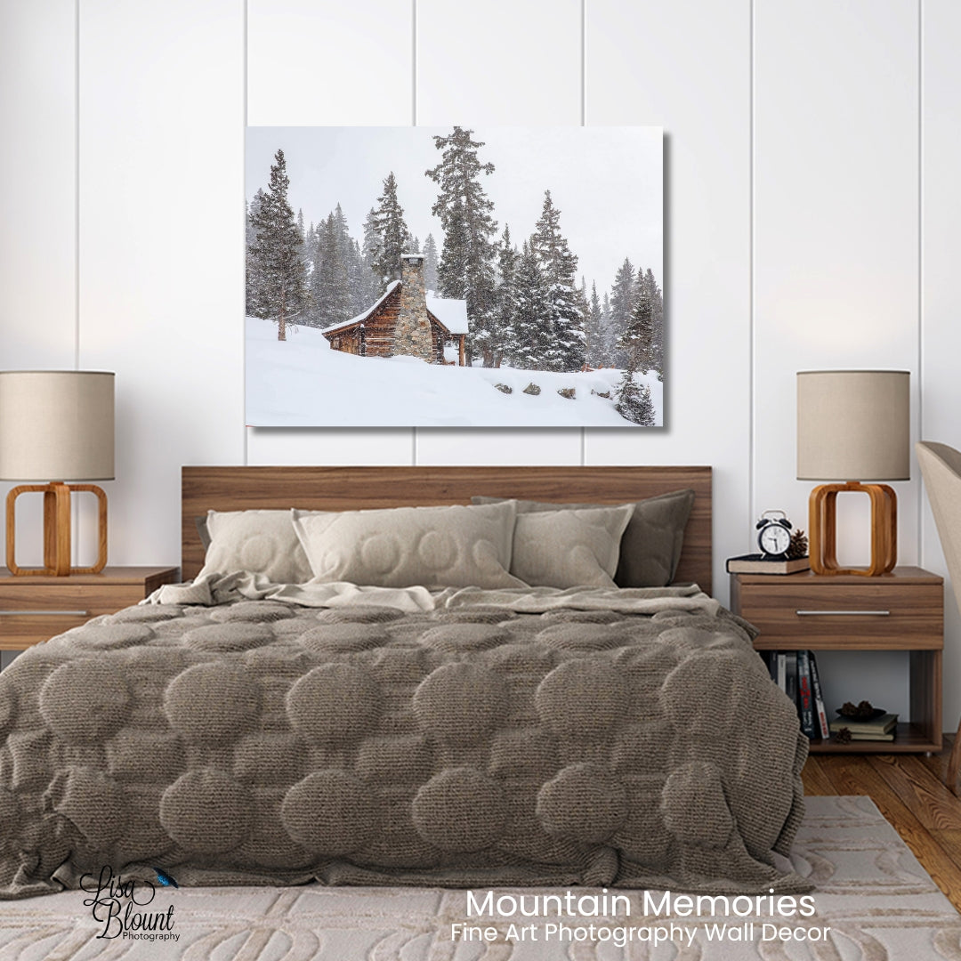 Mountain memories of a snow covered cabin in the mountains of Colorado - large art hanging on a white wall bedroom over a bed with brown accents.