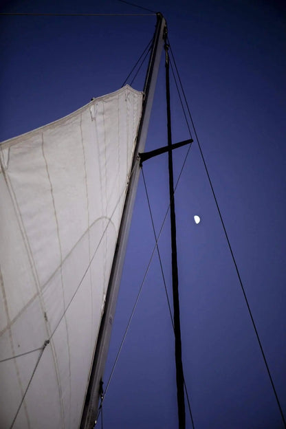 Large art of sailboat at night with moon shining thru lines